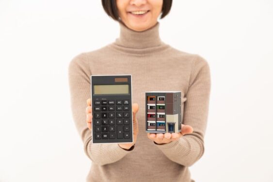 マンションの模型と電卓を持つ女性